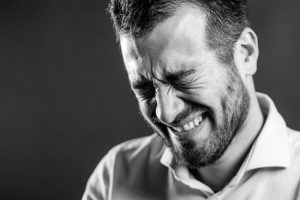 Man closing eyes in strange feeling of agony